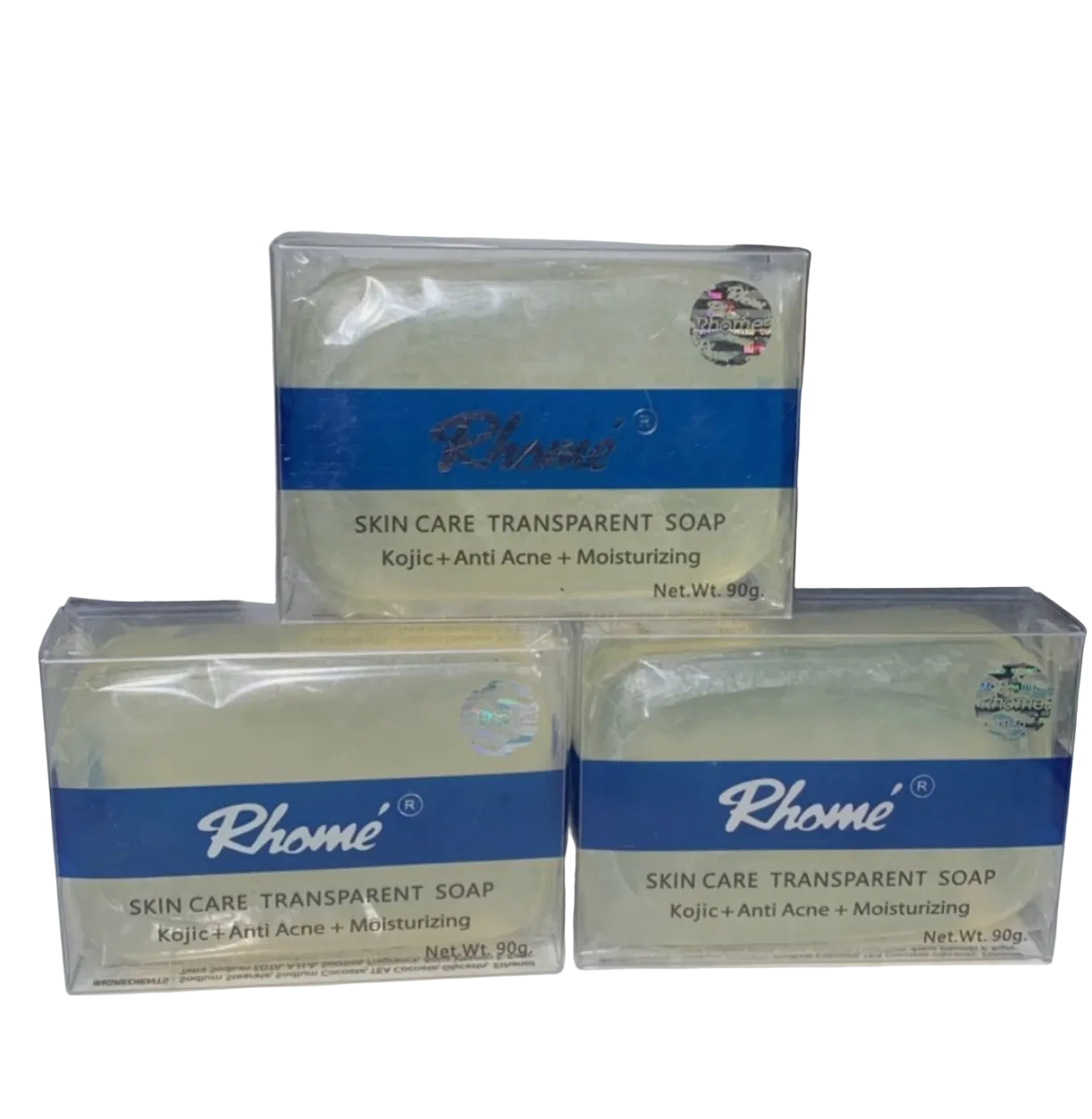 Three bars of Rhomé skin care transparent soap on a white surface with a blurred background.